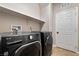 Bright laundry room with modern washer and dryer, practical shelving and an access door at 10733 Red Badge Ave, Las Vegas, NV 89166