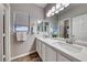 Modern bathroom features double sinks, gray walls, a large mirror, and wood look flooring at 11334 Patores St, Las Vegas, NV 89141