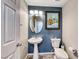 Charming half bathroom features blue accent wall, pedestal sink, round mirror and tile flooring at 11334 Patores St, Las Vegas, NV 89141