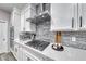 Modern kitchen with stainless steel gas range, gray backsplash, and white cabinets at 11334 Patores St, Las Vegas, NV 89141