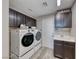Laundry room featuring a front load washer and dryer, dark cabinets and a utility sink at 11334 Patores St, Las Vegas, NV 89141