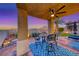 Inviting covered patio featuring a stylish seating area, ceiling fan, and picturesque desert views at 11334 Patores St, Las Vegas, NV 89141