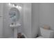 Compact bathroom featuring a pedestal sink, round mirror, and a toilet at 12 Golden View St, Henderson, NV 89012