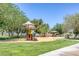 Community playground featuring colorful slides and climbing structures surrounded by mature trees and green grass at 12 Golden View St, Henderson, NV 89012