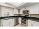 Galley kitchen featuring stainless steel appliances, white cabinets, and a convenient pass-through window at 1393 Calmview Pl, Las Vegas, NV 89110