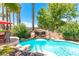 Inviting pool area featuring a rock waterfall, complemented by lush greenery and a nearby patio seating at 179 Adomeit Dr, Henderson, NV 89074
