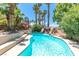 Resort-style backyard with a sparkling pool, rock waterfall, and a cozy seating area under a red umbrella at 179 Adomeit Dr, Henderson, NV 89074