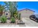 Charming single-story home with a two-car garage, desert landscaping, and mature trees, providing curb appeal at 2402 Saguaro Point St, Las Vegas, NV 89115