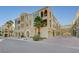Exterior view of multi-story building with tan stucco, arched entryways, and lush palm trees at 2555 Hampton Rd # 5104, Henderson, NV 89052