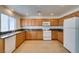 Well-lit kitchen with wood cabinets, granite counters, tile flooring, and a modern white refrigerator at 2786 Fountain Ridge Ln, Henderson, NV 89074