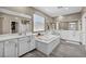 Bright bathroom featuring dual sinks, a soaking tub, a privacy window, and wood-look floors at 3195 Hazy Hills Ave, Henderson, NV 89052