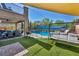 Backyard with a covered patio, a sparkling pool, an egg chair, and an artificial grass area at 3195 Hazy Hills Ave, Henderson, NV 89052