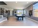 Spacious game room with a pool table, light hardwood floors, neutral colored walls, and large windows for ample natural light at 352 Angels Trace Ct, Las Vegas, NV 89148