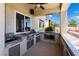 Outdoor kitchen featuring a built-in grill, pizza oven, sink, stainless steel storage, and counter seating at 352 Angels Trace Ct, Las Vegas, NV 89148