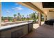 Covered outdoor kitchen with stainless steel appliances, bar seating, and views of the golf course at 352 Angels Trace Ct, Las Vegas, NV 89148