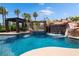 Resort-style pool with rock waterfall, spa, slide, and covered patio area surrounded by lush landscaping at 352 Angels Trace Ct, Las Vegas, NV 89148