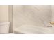 Close-up of the bathtub with a clean white tile surround, a toilet, and stylish gold fixtures at 3748 Silent Hill Dr, Las Vegas, NV 89147