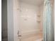 Tiled bathtub with shower in a well-lit bathroom with patterned curtain and built in shelving at 3790 W Moberly Ave, Las Vegas, NV 89139