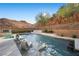A pool sits near a desert hillside; the pool is complemented by chaise lounges and shade trees at 5 Highland Cove Ln, Henderson, NV 89011