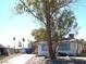 Exterior shot of a single-story home featuring light siding and a front yard with mature trees at 5068 Killarney St, Las Vegas, NV 89122