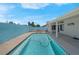 A clear blue pool surrounded by a concrete patio with a covered patio and a blue privacy wall at 519 Landra Ln, Henderson, NV 89015