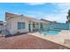 A clear blue pool surrounded by a concrete patio with a covered patio, and a red rock landscape at 519 Landra Ln, Henderson, NV 89015