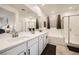 Bright bathroom features double sinks, a bathtub, and a glass-enclosed shower, perfect for a modern lifestyle at 6098 Avery Pointe St, Las Vegas, NV 89166