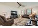 Bright living room featuring a modern ceiling fan, plush leather seating, and a cozy fireplace at 6098 Avery Pointe St, Las Vegas, NV 89166
