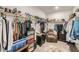 Walk-in closet with organized hanging rods and shoe racks offering ample storage, enhanced by a cozy recliner at 6098 Avery Pointe St, Las Vegas, NV 89166