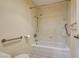 Bathtub with shower featuring safety bars, shower caddy, and textured wall surround at 6822 Garden Grove Ave, Las Vegas, NV 89103