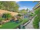 Lush backyard showcasing pool with rock waterfall and firepit, accented by faux grass at 69 Tapadero Ln, Las Vegas, NV 89135