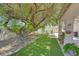 Relaxing backyard featuring a comfortable bench, a large tree, artificial grass, and potted plants at 6920 Haven Hollow Ave, Las Vegas, NV 89130