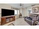 Comfortable living room with tile floors, large windows, a ceiling fan, and an entertainment center at 7019 Shadow Crest Dr, Las Vegas, NV 89119
