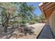 Backyard with mature tree providing shade over a desert landscape and adjacent covered patio at 710 Tomahawk Ct, Pahrump, NV 89060
