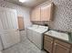 Charming laundry room with floral wallpaper, matching cabinetry, washer, dryer and utility sink at 710 Tomahawk Ct, Pahrump, NV 89060