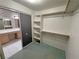 A carpeted walk-in closet with open shelving and rack storage adjacent to the bathroom featuring double sinks at 710 Tomahawk Ct, Pahrump, NV 89060