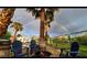 Picturesque backyard with a rainbow, palm trees, and an outdoor fire pit area with chairs at 7675 Butterscotch Ct, Las Vegas, NV 89131