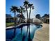 Sparkling pool surrounded by palm trees, a lush green lawn and a white fence at 7675 Butterscotch Ct, Las Vegas, NV 89131
