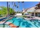 Backyard swimming pool with a waterfall feature, surrounded by lush greenery and seating areas at 7889 Rancho Mirage Dr, Las Vegas, NV 89113