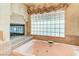 Bathroom bathtub with window above and fireplace, offering a relaxing and luxurious experience at 7889 Rancho Mirage Dr, Las Vegas, NV 89113