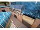 Well-equipped outdoor kitchen with a built-in grill, mini fridge, and tiled bar, perfect for outdoor entertaining at 7889 Rancho Mirage Dr, Las Vegas, NV 89113
