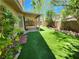 Backyard with a covered patio, artificial grass, and mature landscaping, creating a serene outdoor space at 9052 Pine Mission Ave, Las Vegas, NV 89143