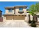 Tan two-story home featuring a three-car garage and desert landscaping under a clear blue sky at 9052 Pine Mission Ave, Las Vegas, NV 89143