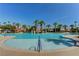 Expansive community pool with clear blue water, surrounded by palm trees and a splash park at 907 Gallery Course Dr, Las Vegas, NV 89148