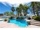 Beautiful backyard pool and spa area with rock features, lush landscaping, and mature palms at 9155 Harvest Homes St, Las Vegas, NV 89123