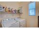 A laundry room features a Whirlpool washer and dryer, shelf space, and natural light at 9715 Aleutian St, Las Vegas, NV 89178