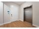 Hallway featuring a white entry door with a stainless steel elevator on wood flooring at 128 Los Cabos Dr # 202, Las Vegas, NV 89144