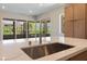 Modern kitchen island with stainless steel sink and faucet, quartz countertops, and view of the outside balcony at 128 Los Cabos Dr # 202, Las Vegas, NV 89144