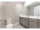 Bathroom showcasing a toilet and sink with gray cabinetry, complete with a large mirror at 128 Los Cabos Dr # 302, Las Vegas, NV 89144