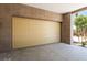 Garage entrance featuring a tan sectional door, brick pillars, and garden view at 128 Los Cabos Dr # 302, Las Vegas, NV 89144